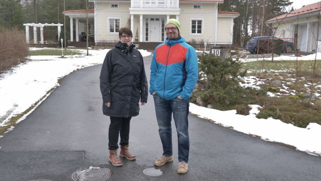 Ett par står utanför ett egnahemshus i Nagu på vintern.